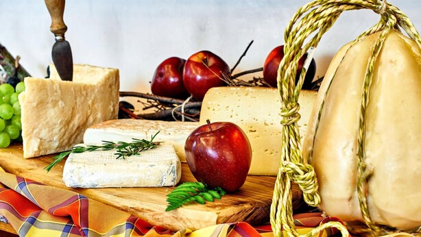 A variety of cheeses and fruits on a wooden board. - Costa (Costa Valle Imagna)