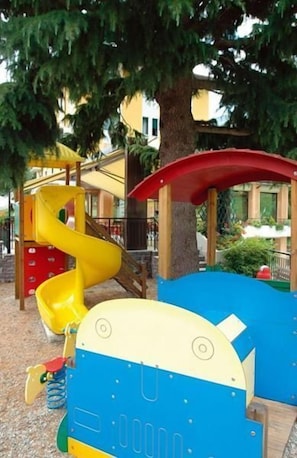 Ein Spielplatz mit einer gelben Rutsche und einer blauen Kletterkonstruktion.
