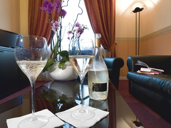 Una mesa con dos copas de champagne, una botella de vino y un florero con orquídeas.