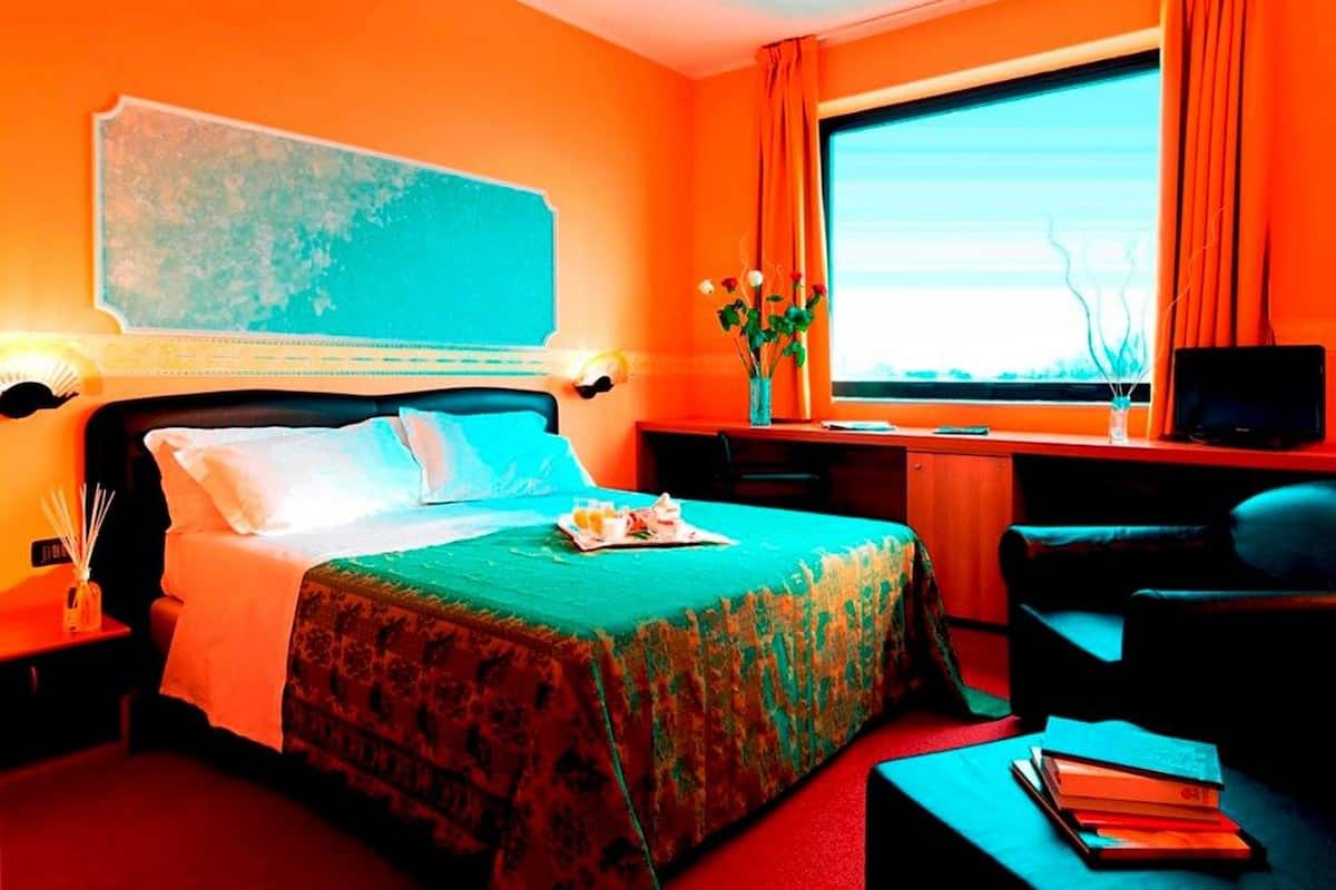 Een hotelkamer met een bed, bureau, stoel, televisie en raam met gordijnen.