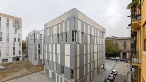 Un edificio moderno con fachada enrejada, amplios ventanales y techo plano.