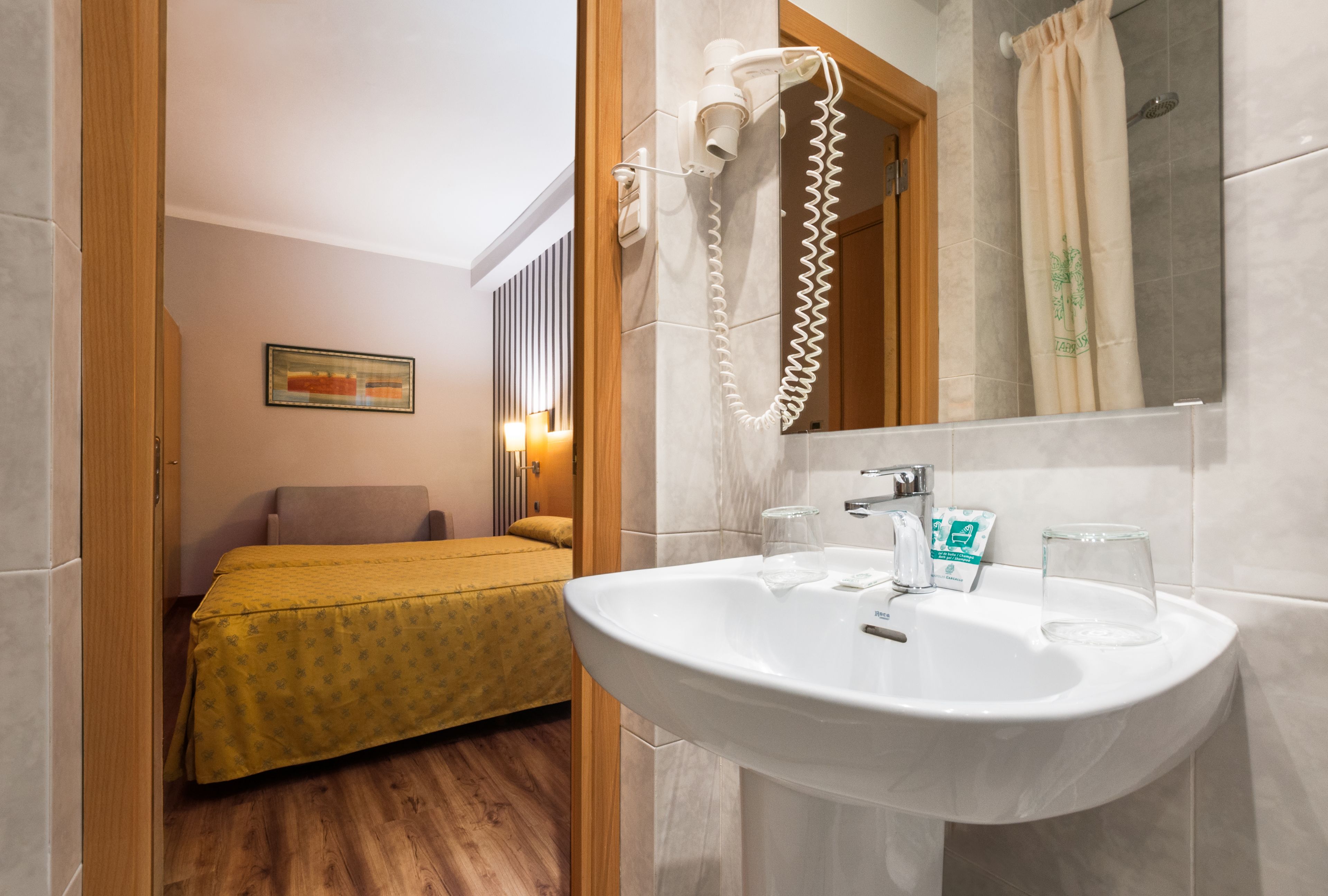 Een hotelkamer met een bed, een badkamer met een wastafel en een douche.