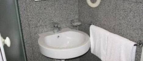 A bathroom with a white sink, a mirror, and a towel hanging on a rack.