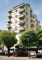 A multi-story building with balconies, a sign reading "HOTEL," and a green awning.