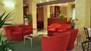 Eine Lobby mit roten Sesseln, einem Glastisch und einem Empfangsbereich.
