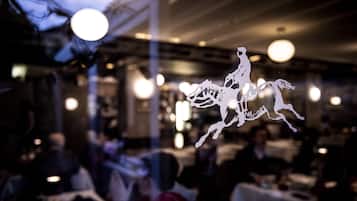 L’intérieur d’un restaurant, avec des tables et des chaises, un éclairage tamisé et des luminaires suspendus.