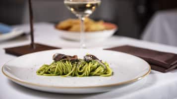 A plate of pasta with a glass of white wine on a table.