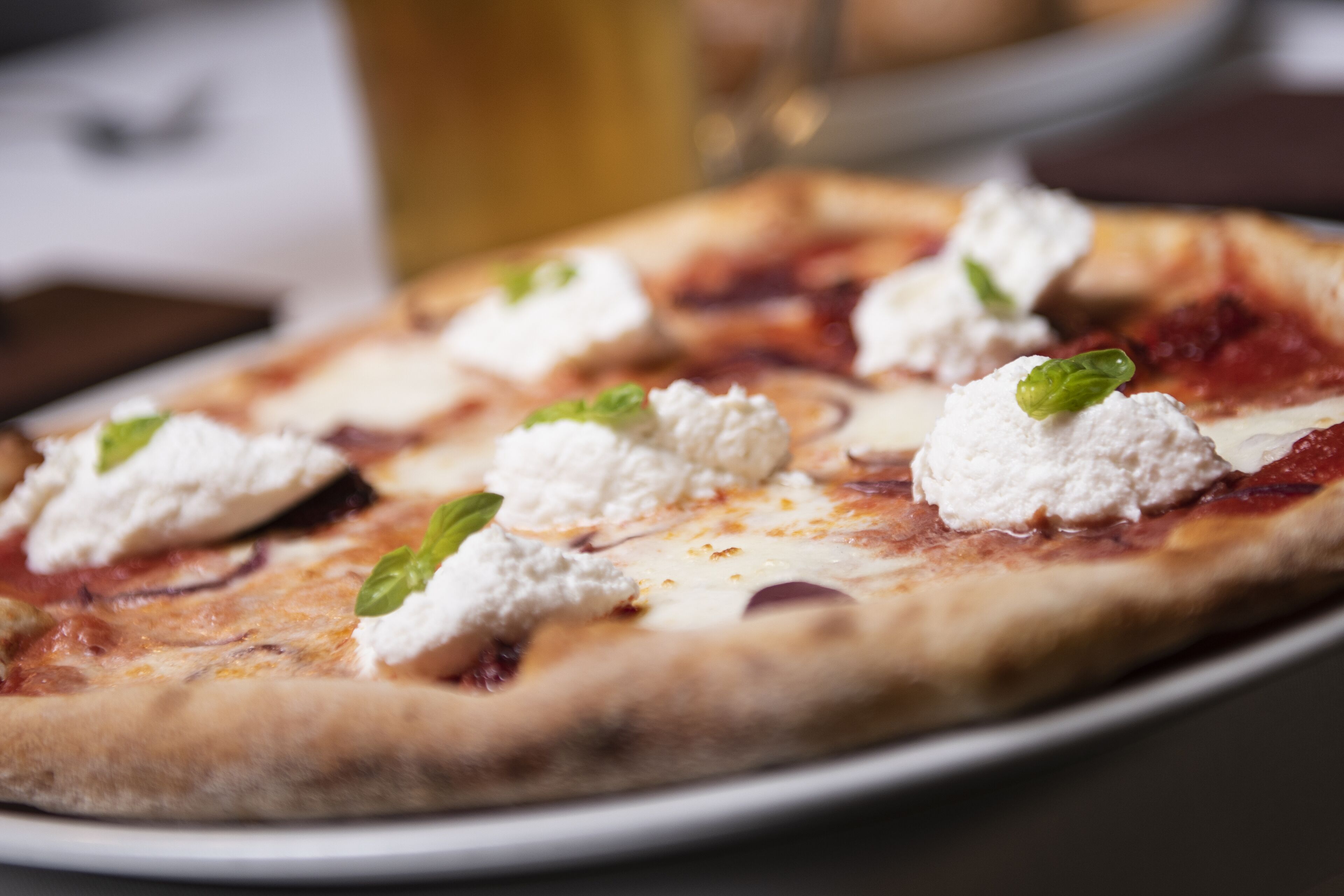 A pizza with cheese and basil on a plate.