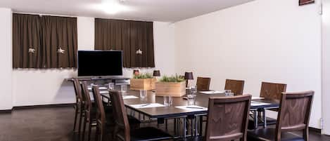 A conference room with a large table, chairs, a television, and curtains.