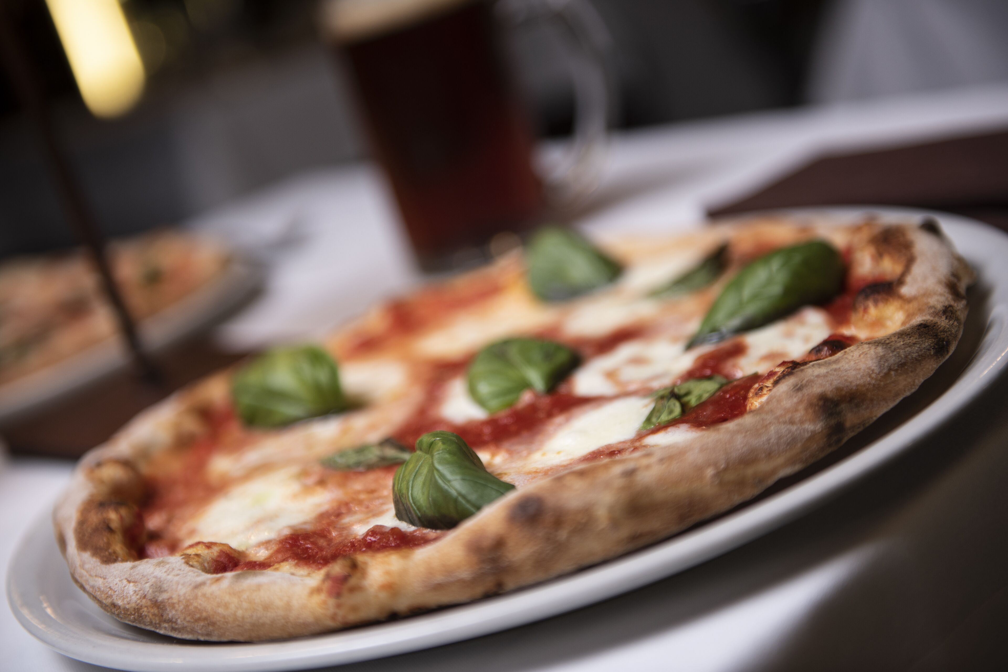 A pizza with basil leaves on a white plate.