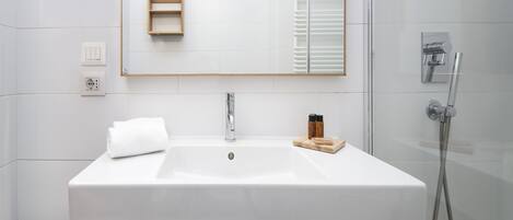 A modern bathroom with a white sink, a mirror, and a shower.