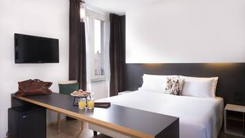 A hotel room with a bed, a desk with breakfast, a TV, and a window with curtains.