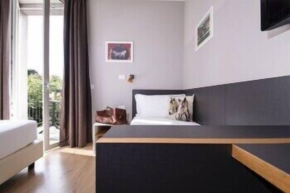 Een moderne hotelkamer met een bed, een bureau, een stoel en uitzicht op het omliggende landschap.