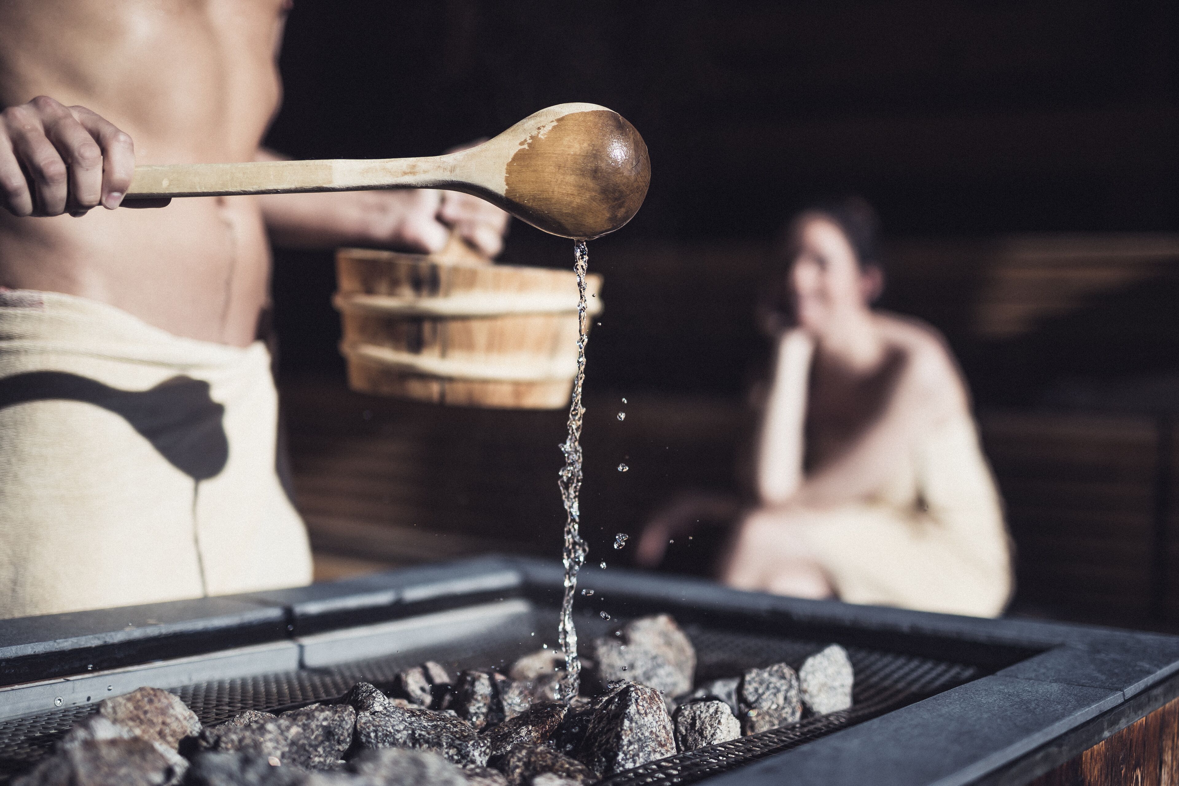 A person pouring water over charcoal in a grill.