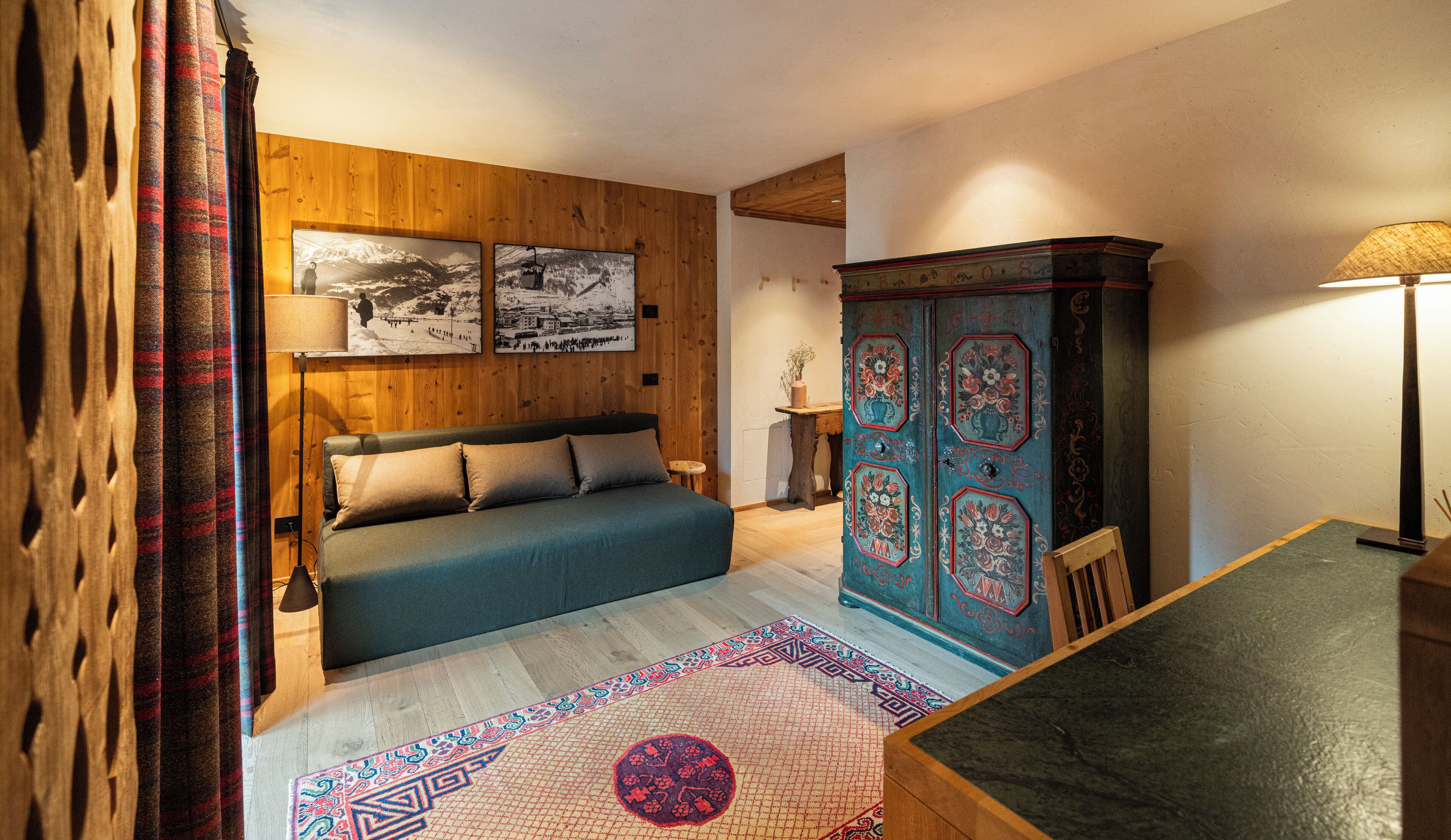 A cozy bedroom with a bed, wooden walls, a decorative cabinet, and a rug.