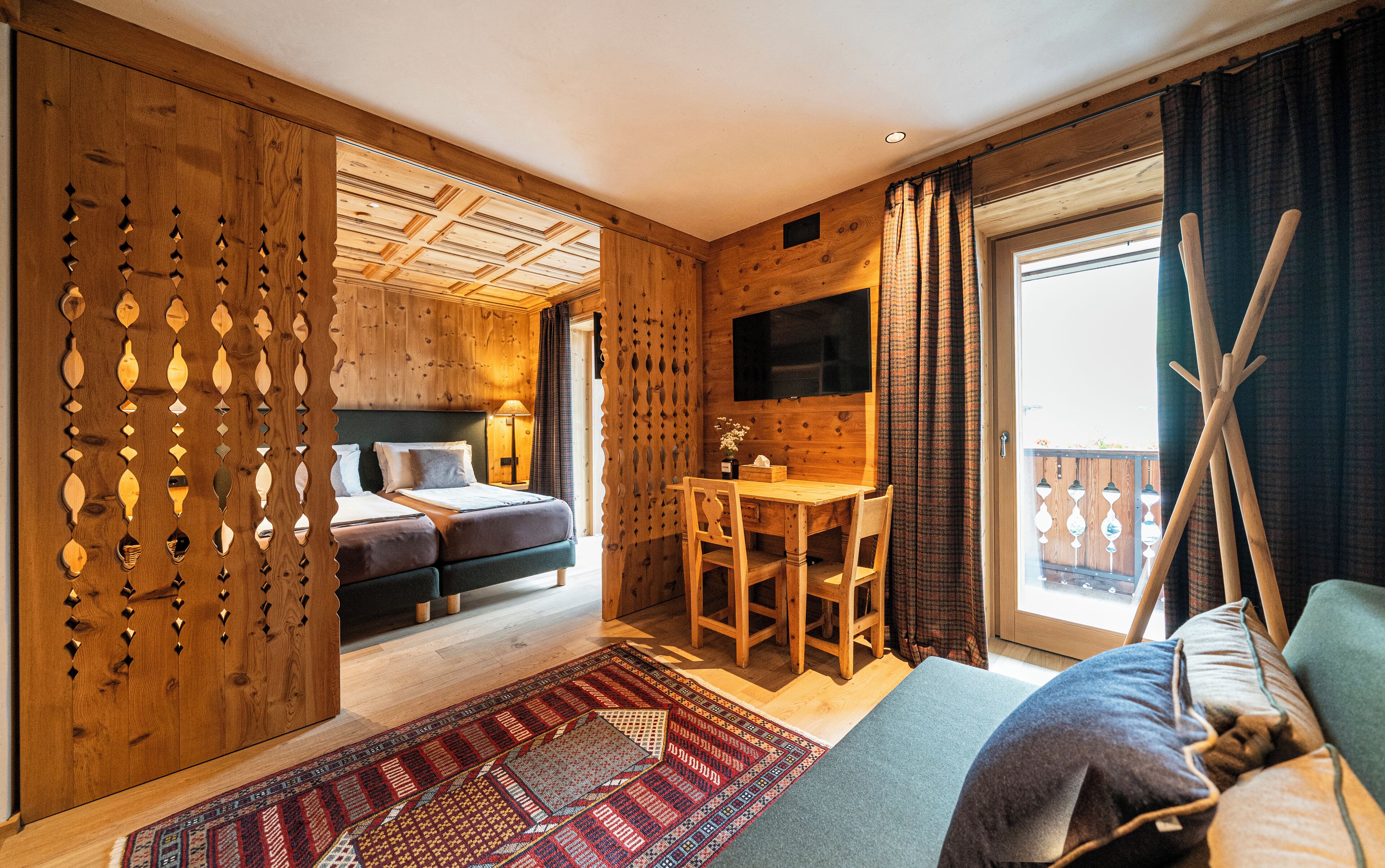 Una habitación de cabaña de madera con una cama, un escritorio y un televisor.