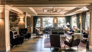 A spacious living room with a fireplace, comfortable seating, and large windows offering a view of the outdoors.
