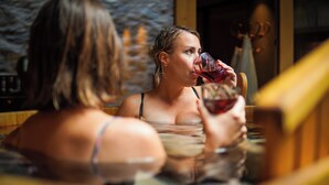 A woman in a hot tub with a wooden interior and stone wall backdrop.
