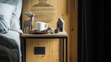 Una mesita de noche de madera con una lámpara, una taza, un modelo de casa y una figurita de reno.