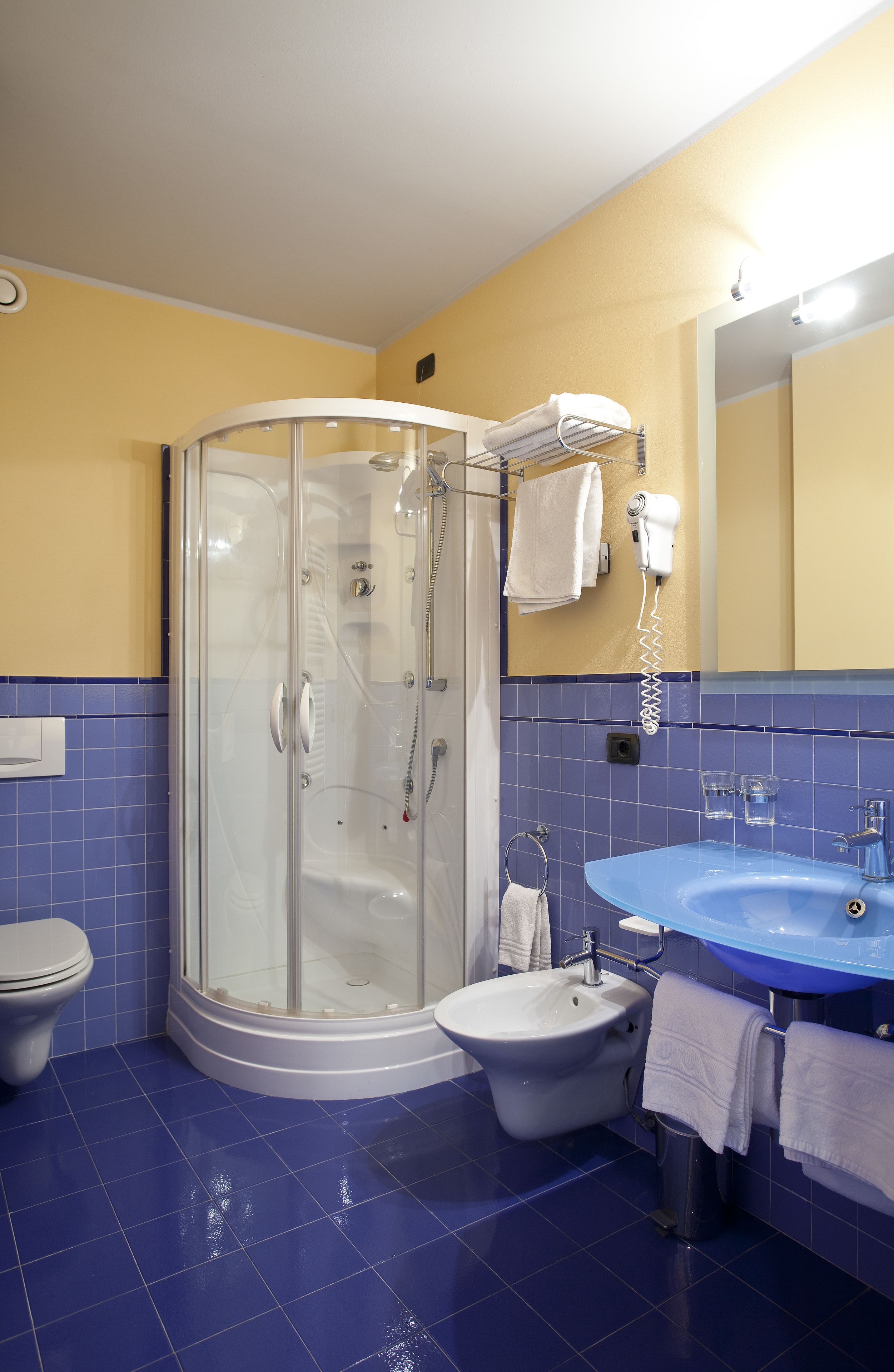A bathroom with a glass-enclosed shower, a pedestal sink, and a toilet.