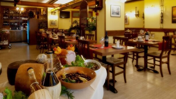 A restaurant interior with wooden tables and chairs, a bar area with bottles, and a buffet table with various dishes and condiments. - Hotel Tre Leoni (Somma Lombardo)
