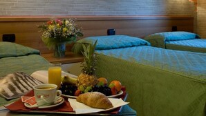 A hotel room with two single beds, a breakfast tray with croissant, fruit, and orange juice, and a vase of flowers on the nightstand. - Hotel Tre Leoni (Somma Lombardo)