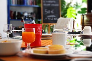 Una mesa de desayuno con una taza roja, un vaso de jugo de naranja, una taza blanca y un plato con pasteles.