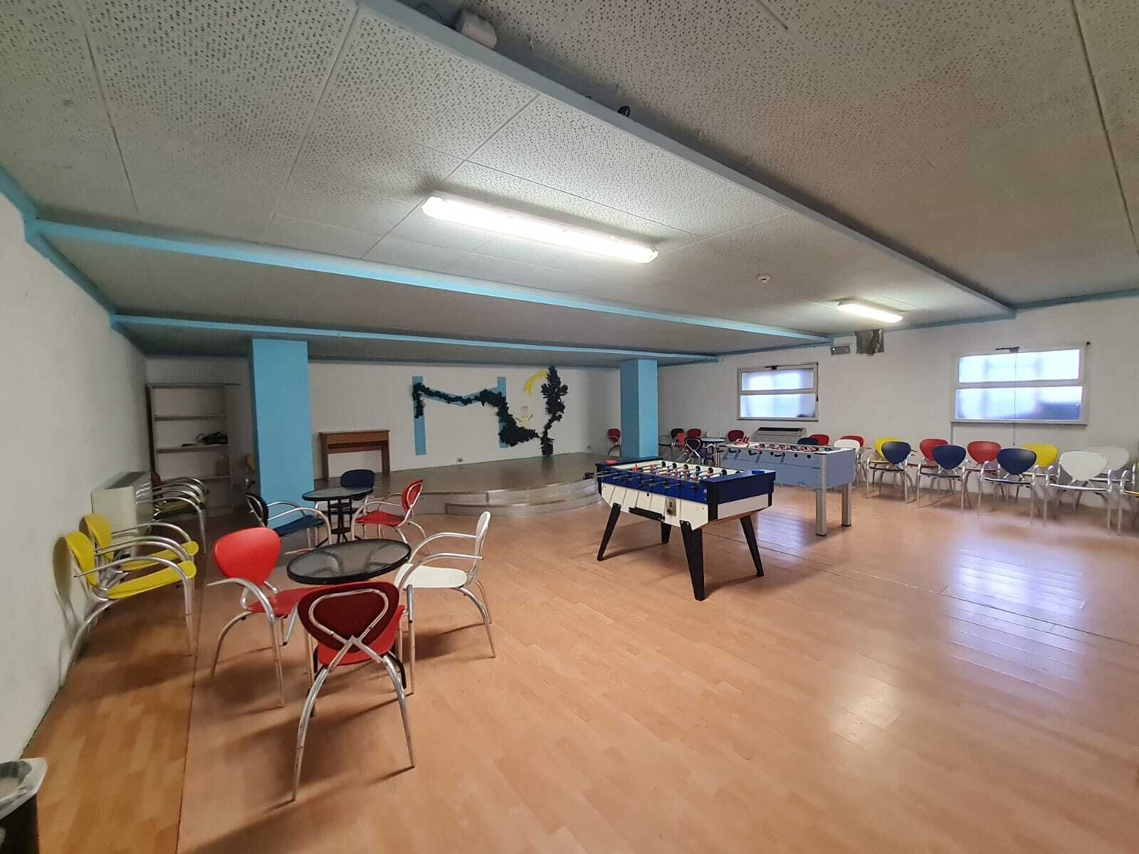 Une pièce avec un plancher en bois, une table de baby-foot et plusieurs chaises.