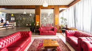 A lobby with red leather sofas, a wooden coffee table, and a patterned rug.