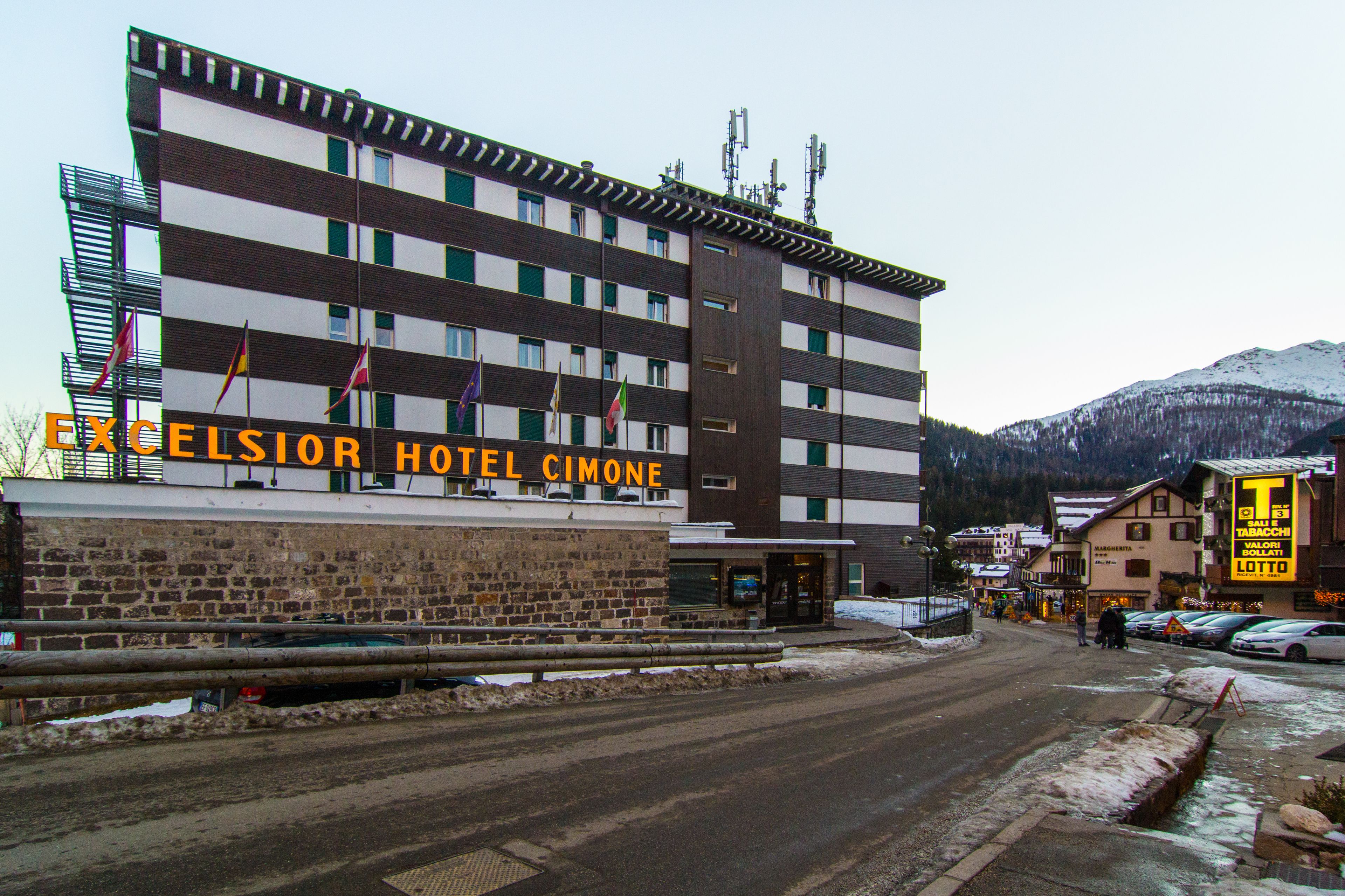 A multi-story hotel with a sign reading "EXCELSIOR HOTEL CIMONE."