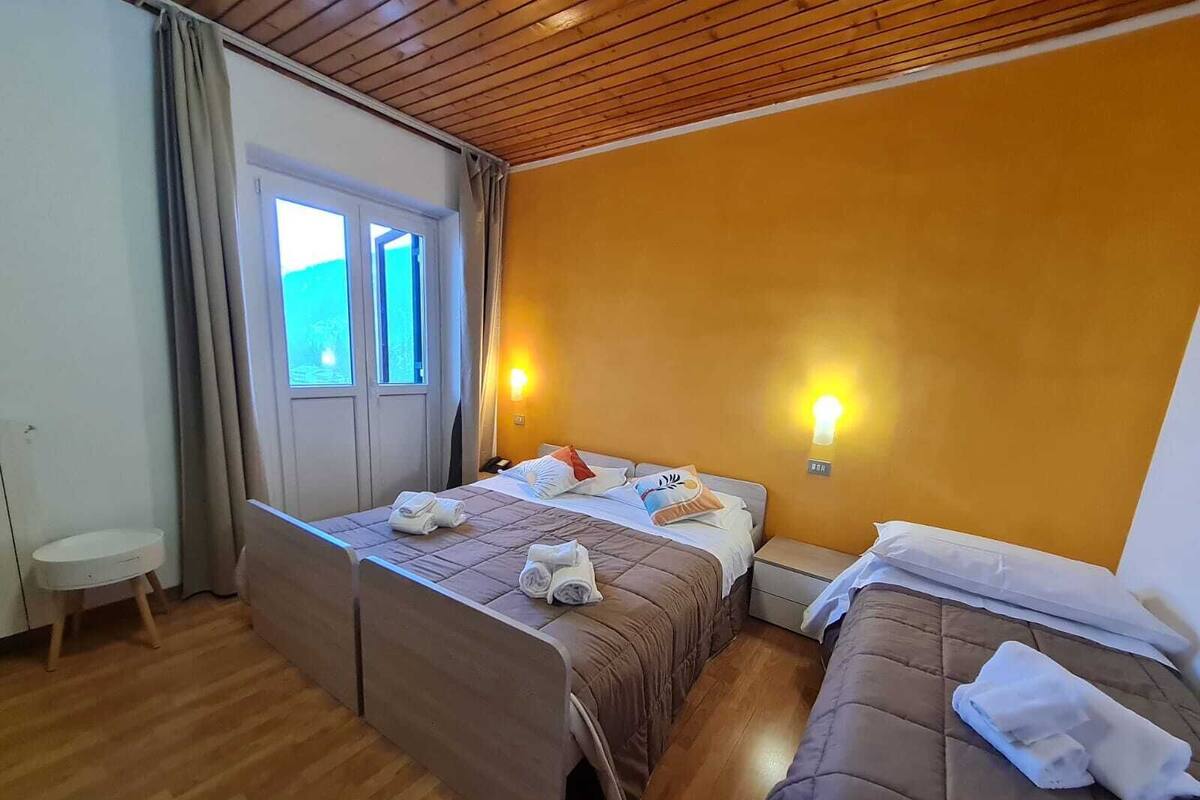 Een hotelkamer met twee bedden, een klein tafeltje, een stoel en een raam met gordijnen.