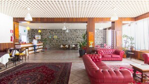 A spacious lobby with a stone wall, a reception desk, a red sofa, and a large patterned rug.