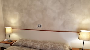 Une chambre d’hôtel avec un lit, deux tables de chevet, une lampe sur chacune des tables et un téléphone sur l’une des tables.