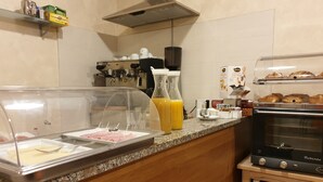 Un bar à petit-déjeuner avec un espace en libre-service, une machine à café et un présentoir rempli de viennoiseries.