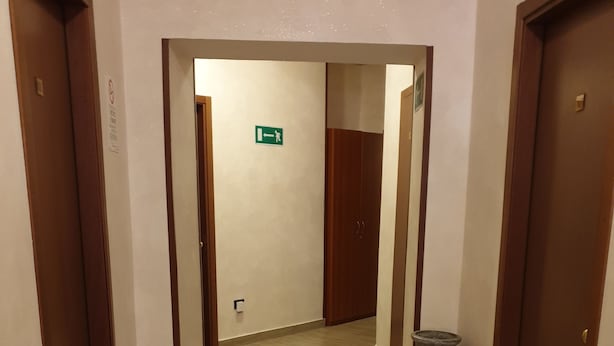 Un couloir avec des portes en bois, un sol carrelé et un vase sur la droite.