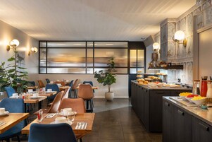 Un comedor moderno con mesas, sillas y una encimera de cocina con alimentos.