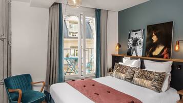 A hotel room with a bed, a chair, a balcony, and artwork on the wall.