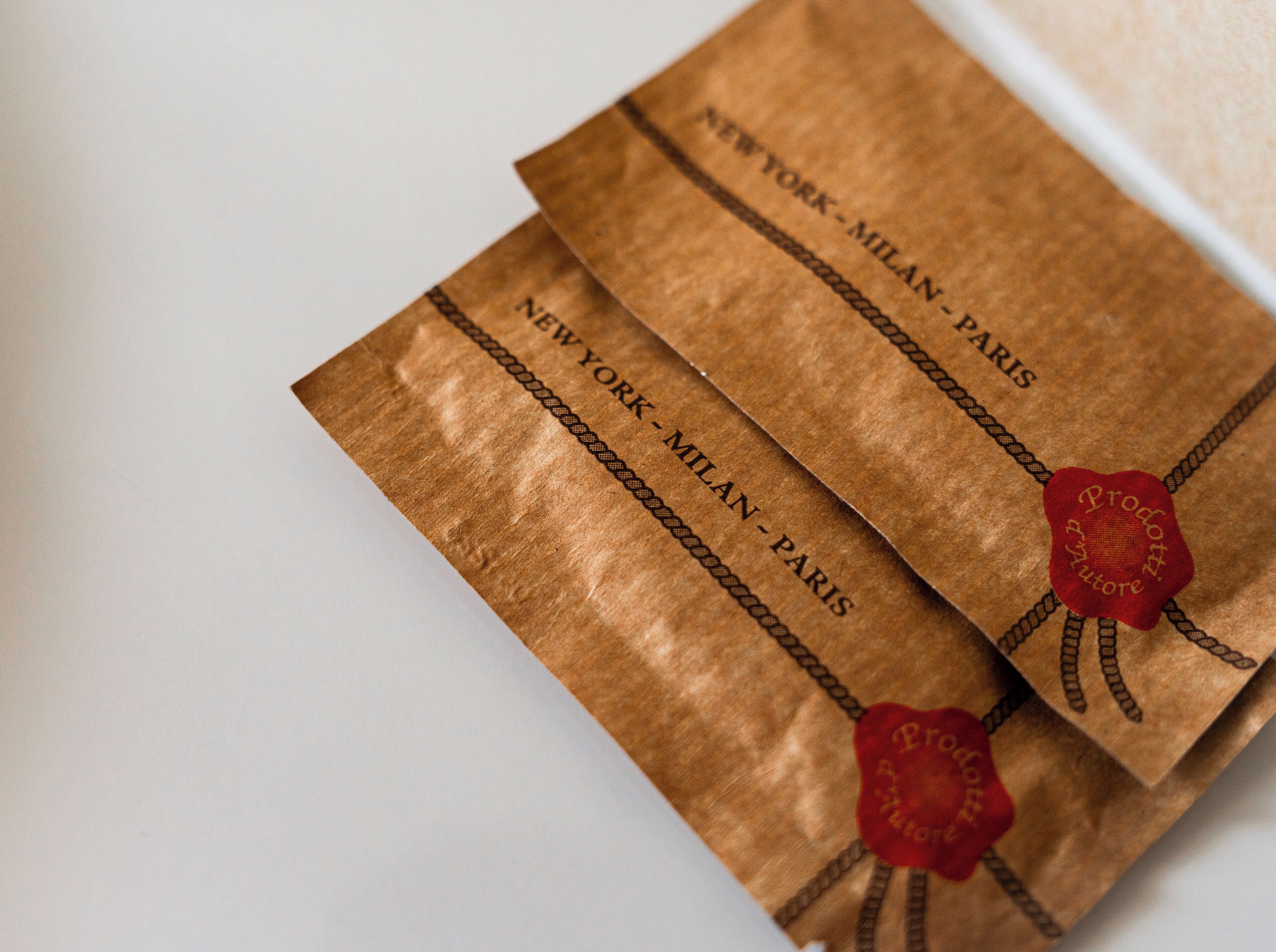 Two brown paper bags with "NEW YORK-MILAN-PARIS" printed on them.