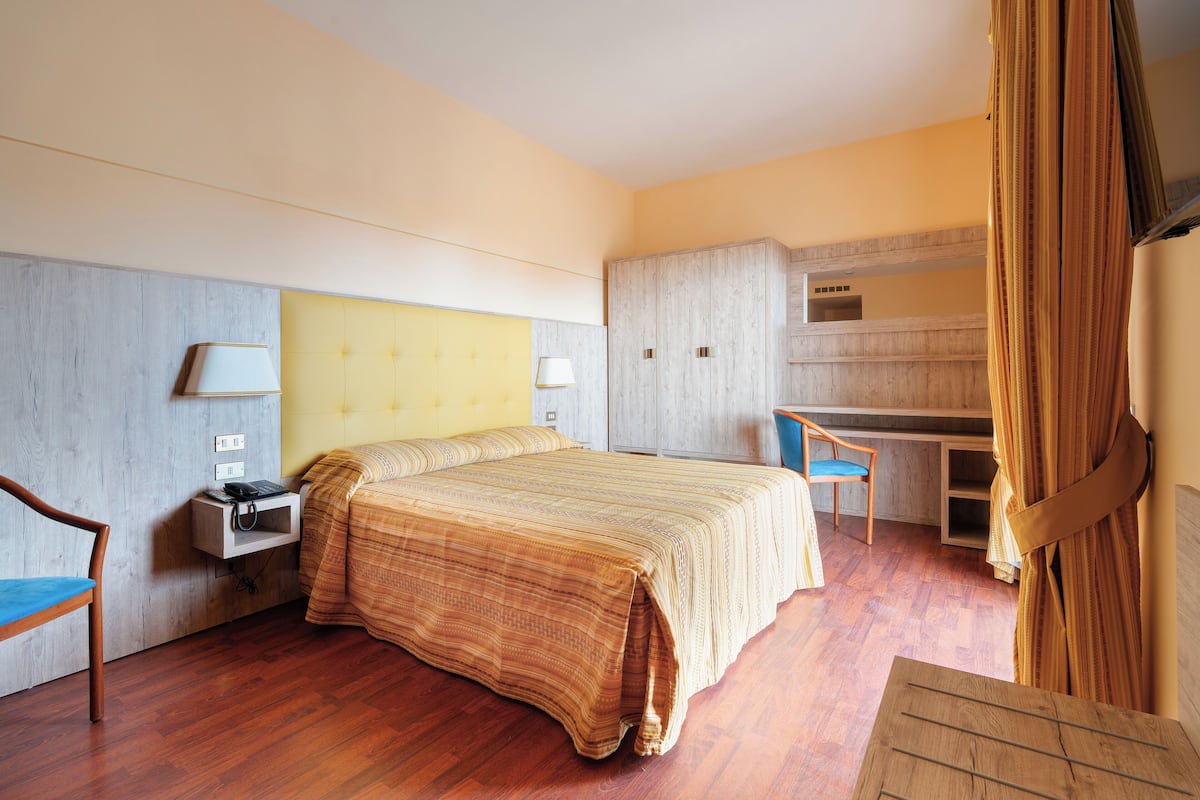 Une chambre d’hôtel avec un lit, un bureau, une chaise et une petite table.