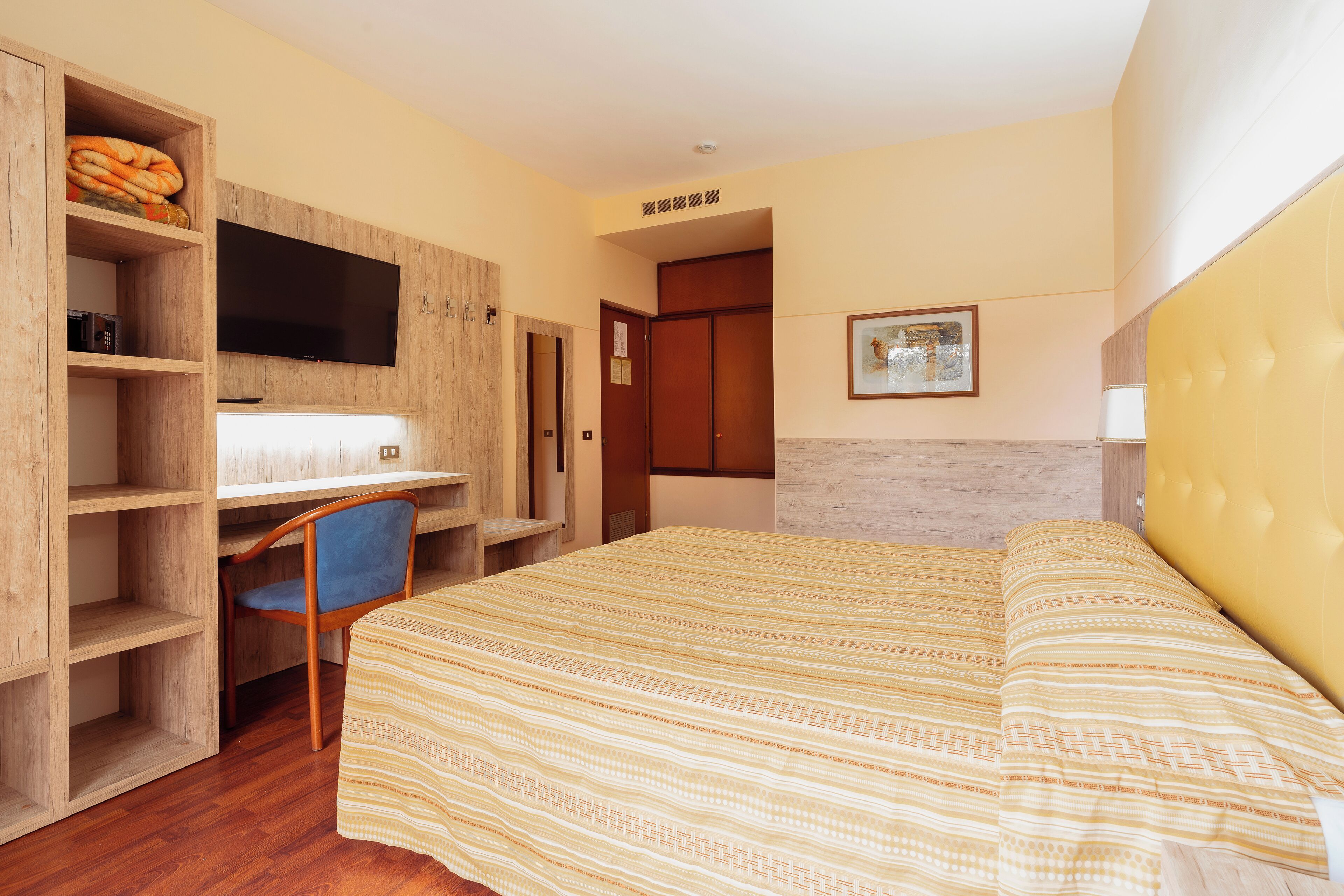 Un dormitorio con cama, escritorio, silla, televisor y armario.