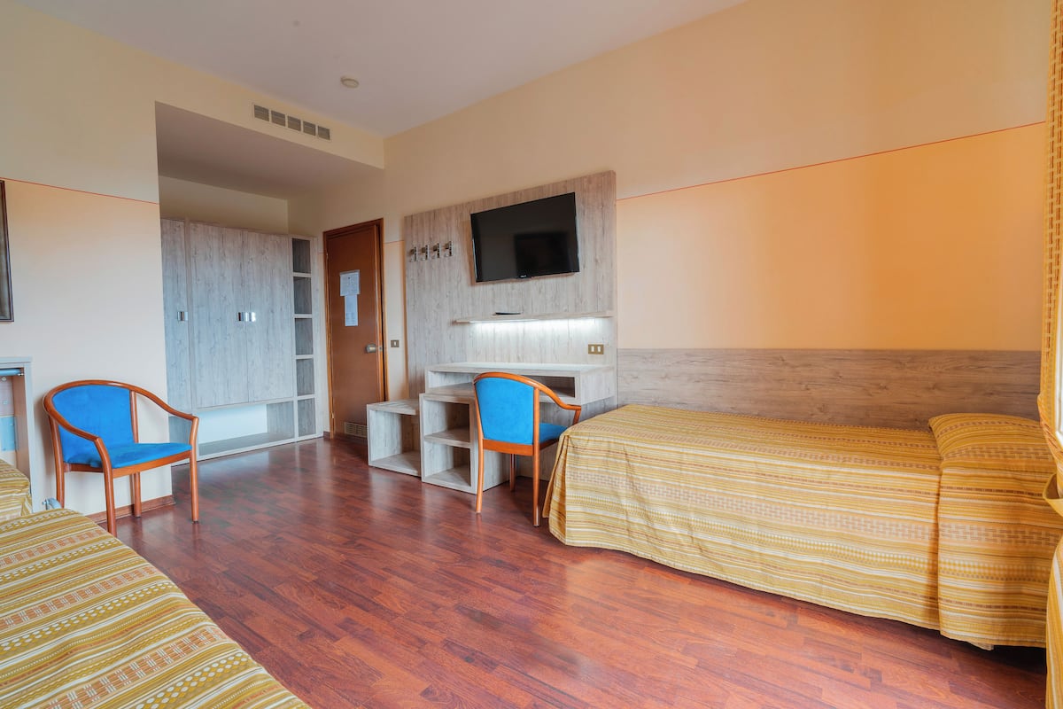 Une chambre d’hôtel équipée d’un lit, d’un bureau, d’une chaise et d’un téléviseur fixé au mur.