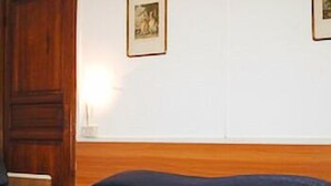A bedroom with a wooden headboard, a bed with a blue cover, and a framed picture on the wall. - Hotel Fernanda (Rapallo)