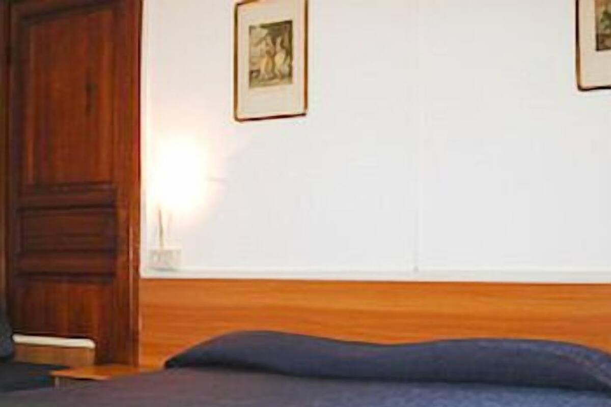 A bedroom with a wooden headboard, a bed with a blue cover, and a framed picture on the wall.