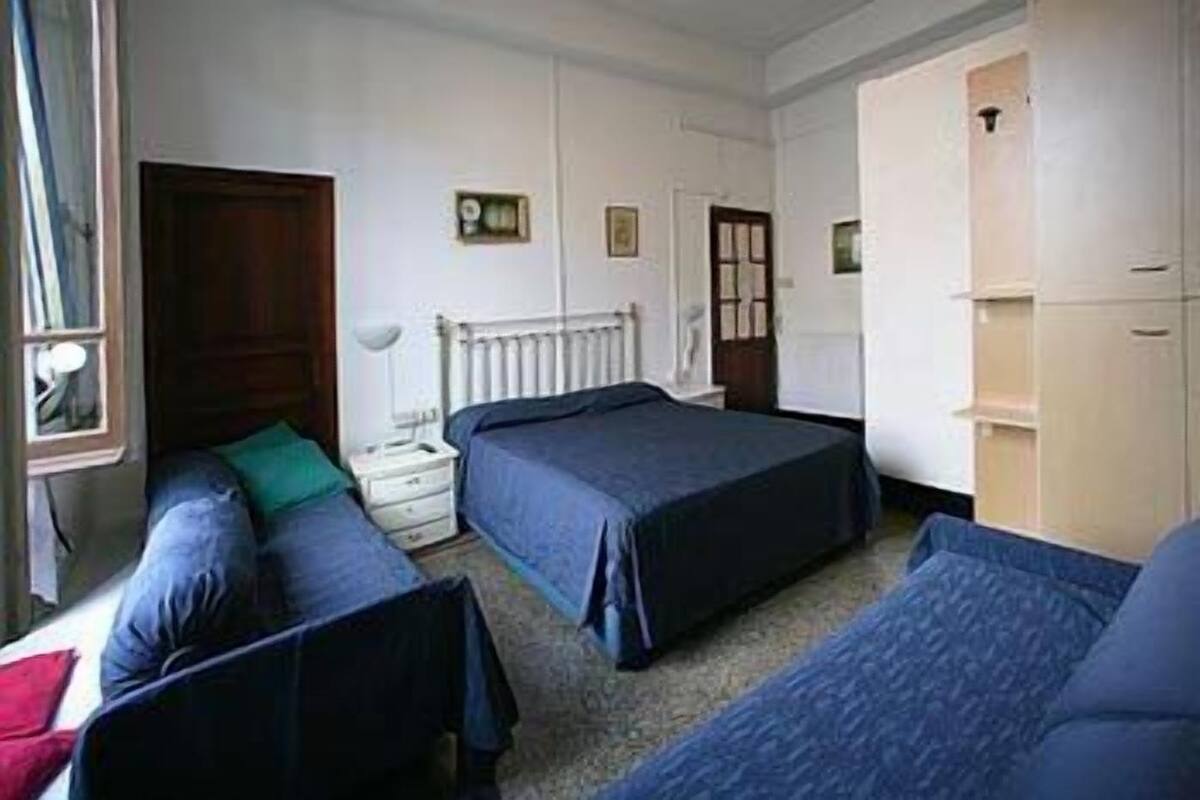 A room with two beds, a nightstand, a radiator, and a wardrobe.