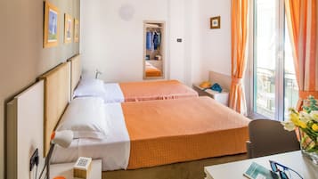 Una habitación de hotel con dos camas, un escritorio, una silla, una lámpara de escritorio, un teléfono y una ventana con cortinas.