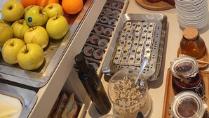 Un bufé con diversos alimentos, entre ellos frutas, pastelería y salsas.