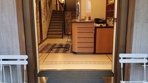 Entrada de un hotel con mostrador de recepción, una escalera y zona alfombrada.