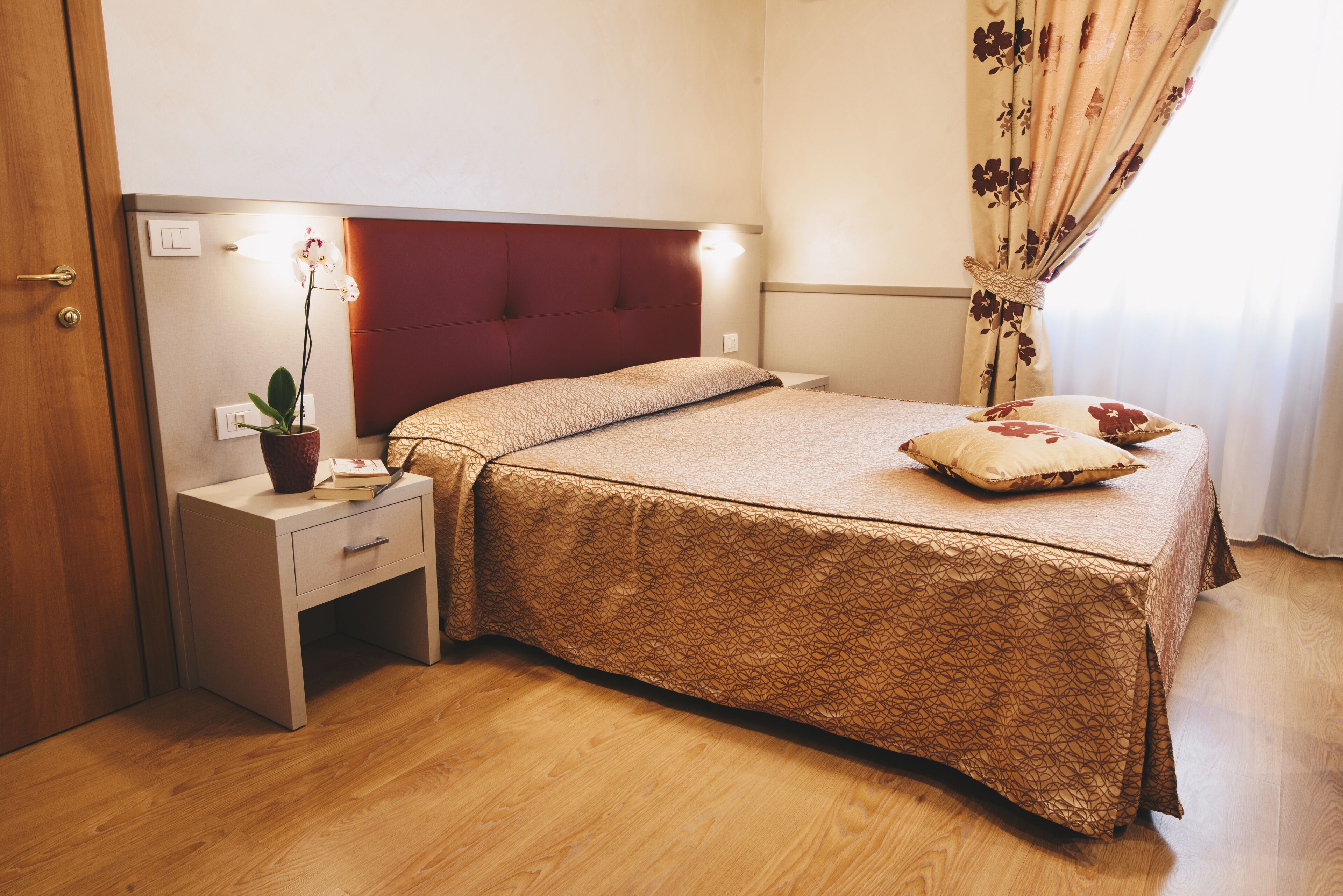 Un dormitorio ordenado con cama, mesita de noche y velador.