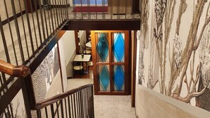 Una escalera con barandilla de madera y una puerta de vidrio con paneles de forma de rombo azul.