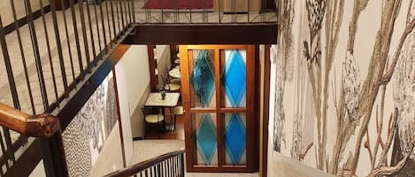 A staircase with a wooden railing and a glass door with blue diamond-shaped panes.